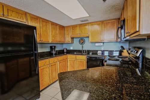 a kitchen with wooden cabinets and a black refrigerator at Phoenix V 902 in Orange Beach