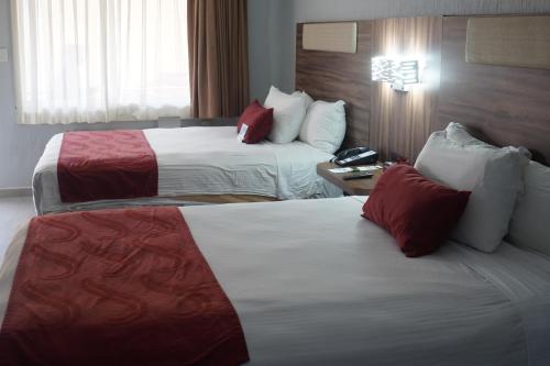 a hotel room with two beds with red pillows at Quality Inn Piedras Negras in Piedras Negras