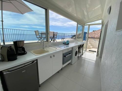 - une cuisine avec évier et vue sur l'océan dans l'établissement Appartement sur l'eau avec clim, plage privée - FR-1-816-5, au Lavandou