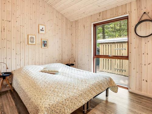 Un dormitorio con una cama y una ventana grande. en 5 star holiday home in Væggerløse, en Bøtø By
