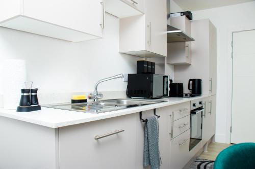 a kitchen with white cabinets and a sink at Modern 2 Bed Flat by Heathrow Airport, Free Parking in Harmondsworth