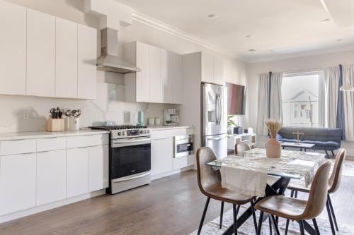 a kitchen with white cabinets and a table with chairs at NYC Gateway, 30minutes from Manhattan in Jersey City