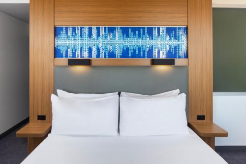 a bedroom with a white bed with a wooden headboard at Aloft Tempe in Tempe