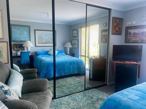 a bedroom with a mirror and a bed and a couch at Art House Blue Room in Huonville