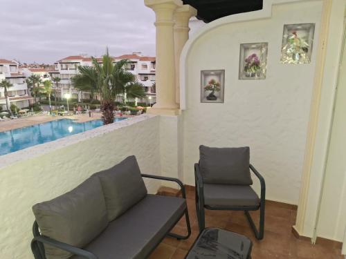 a balcony with a couch and a chair and a pool at Garden Beach 2 sidi rahal in Sidi Rahal