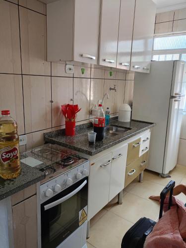 a kitchen with white cabinets and a stove top oven at Praiamongagua in Mongaguá