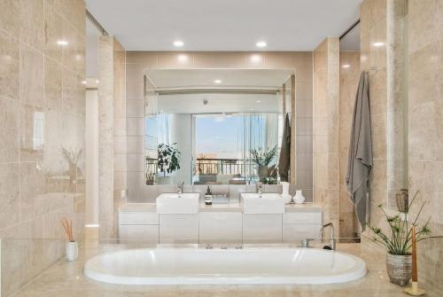 a large bathroom with a tub and a large mirror at Santai Resort - Holiday Management in Kingscliff