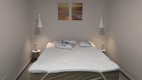 a white bed in a room with two lamps at 50m praia Cond pé na areia Alto padrao 4 suites Segur 24h Costa do sol Guaratuba Bertioga prox Riviera in Bertioga