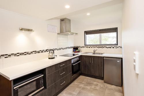 a kitchen with wooden cabinets and a sink and a window at Balmoral Lodge Motel in Invercargill