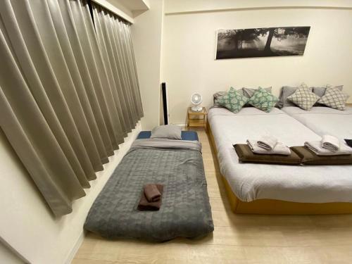 a bedroom with two twin beds and a window at 新大阪徒步30秒 Shinosaka Station 30s, Direct to Kansai Airport 關西空港直達, Universal Studio 16 mins, Umeda 6 mins, Kyoto 25 mins, Early Check in in Osaka