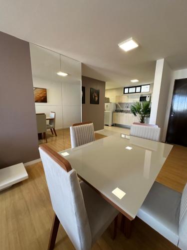 a dining room and living room with a white table and chairs at Apartamento Sua Casa em João Pessoa in João Pessoa