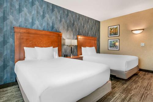 two beds in a hotel room with white sheets at Drury Plaza Hotel Valdosta in Valdosta