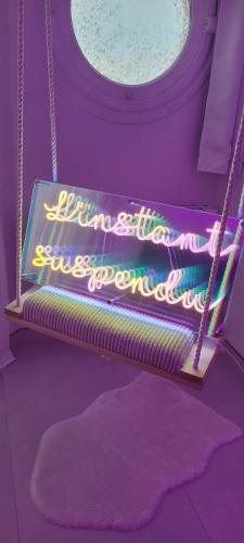 a neon sign on a swing in a room at Love room à 30 mn des plages et de Vannes in Questembert