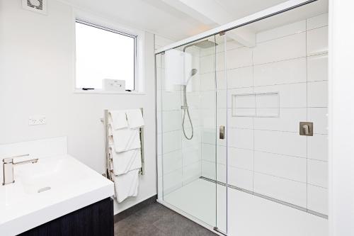 a white bathroom with a shower and a sink at Balmoral Lodge Motel in Invercargill