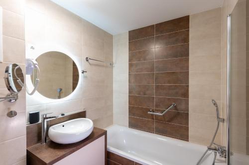 un bagno con vasca, lavandino e specchio di Sunset Resort 003 Jacuzzi a Fonyód