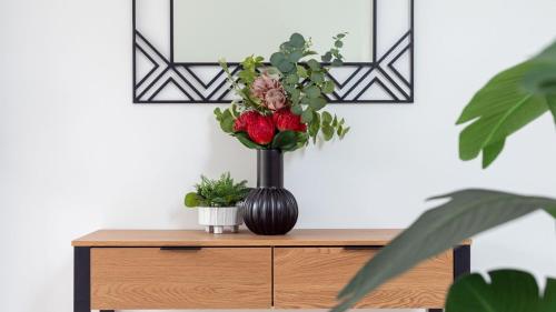 a black vase with flowers on top of a cabinet at Sea Bubbles in Currarong