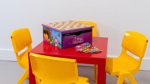 a table with yellow chairs and a toy box on it at Sea Bubbles in Currarong