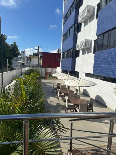 a group of tables and chairs with umbrellas next to a building at Apartamento Sua Casa em João Pessoa in João Pessoa