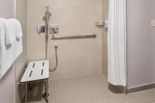 a bathroom with a shower with a bench in it at Courtyard by Marriott Tarrytown Westchester County in Tarrytown