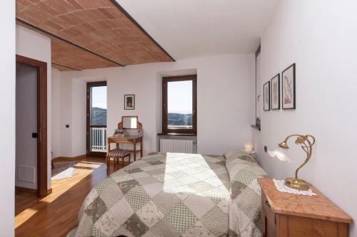 a bedroom with a bed and a desk and windows at C dra Topia the Grape Pergola House near Alba Charming house - Italy in Trezzo Tinella