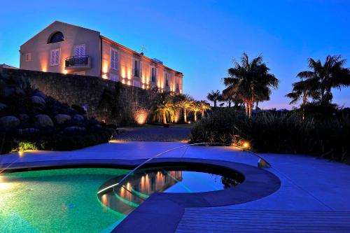 a house with a pool in front of a building at Donna Carmela Resort & Lodges in Riposto