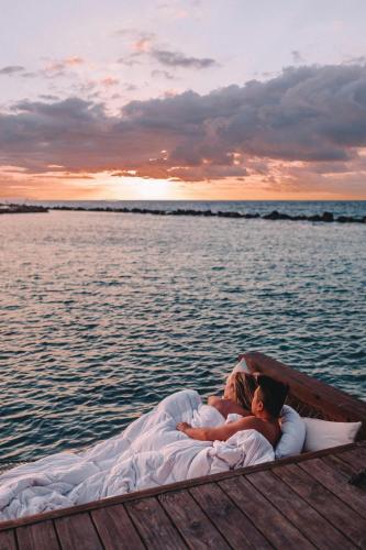 a man and woman laying on a bed in a boat on the water at Renaissance Wind Creek Aruba Resort in Oranjestad