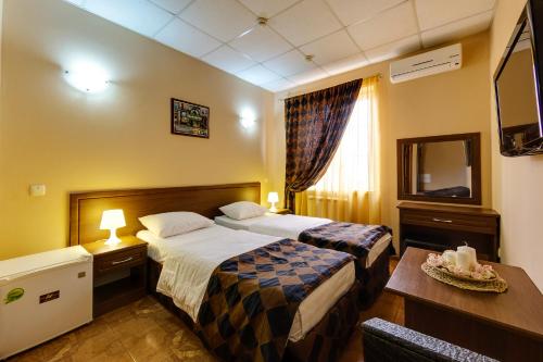 a hotel room with two beds and a television at Marton Amigo Krasnodar in Krasnodar