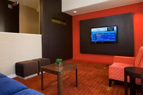 a living room with a tv on a wall at Courtyard by Marriott Baton Rouge Acadian Centre/LSU Area in Baton Rouge
