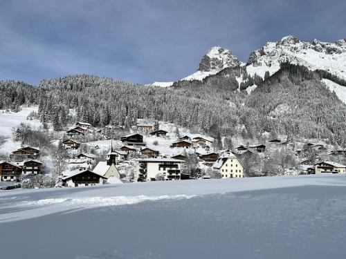 a snow covered village with a mountain in the background at Bachwinkl in Maria Alm am Steinernen Meer