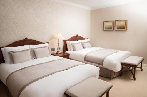 a hotel room with two beds and a chair at Lotte Hotel Jeju in Seogwipo