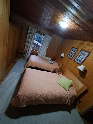 two beds in a room with wooden walls at Hotel los maitenes in Pucón
