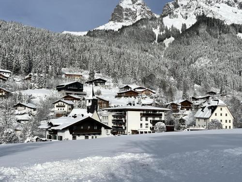 a snow covered village with a mountain in the background at Bachwinkl in Maria Alm am Steinernen Meer