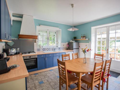 une cuisine avec une table en bois et des armoires bleues dans l'établissement Gite du Verger, à Guignicourt-sur-Vence