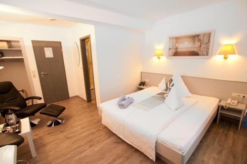 a hotel room with a white bed and a chair at Landgasthaus Bonn in Baunatal
