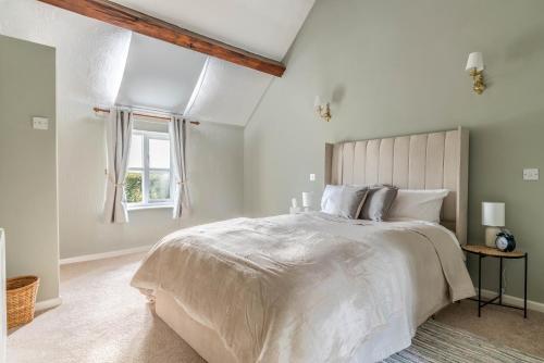 une chambre blanche avec un grand lit et une fenêtre dans l'établissement Millbank Farm Cottage, à Stafford