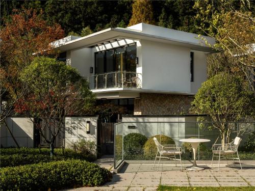 a house with two chairs and a table in front of it at Yibo Jinling Hotel Moganshan in Huzhou