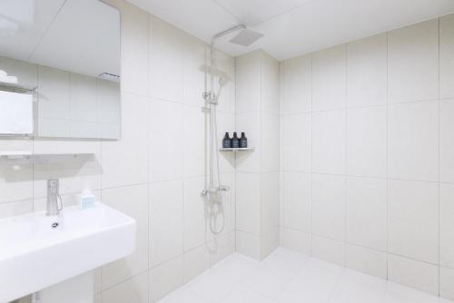 a white bathroom with a shower and a sink at Aank Air Hotel Chuncheon in Chuncheon
