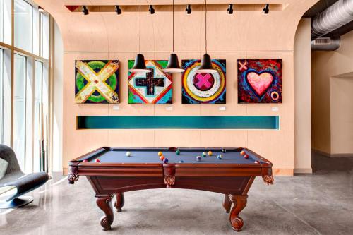 a pool table in a room with paintings on the wall at Aloft Raleigh Durham Airport Brier Creek in Raleigh