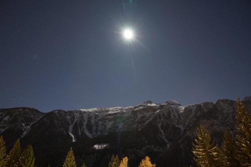 a full moon rising over a mountain at night at Kymera Alpine Apartment in Folgarida