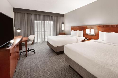 a hotel room with two beds and a desk and a television at Courtyard by Marriott Memphis Airport in Memphis