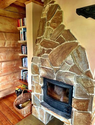 a stone fireplace in a living room with a book shelf at Mountain cozy house in Tatras with stunning view in Ząb