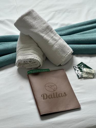 a towel and a wallet and towels on a bed at Hotel Dallas - Penha SC in Penha