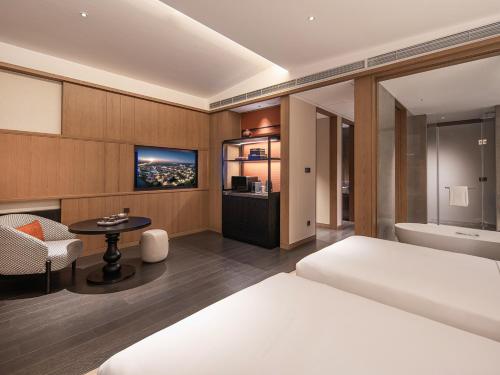 a bedroom with a bed and a tub and a table at Homm Changchun Beihu in Changchun