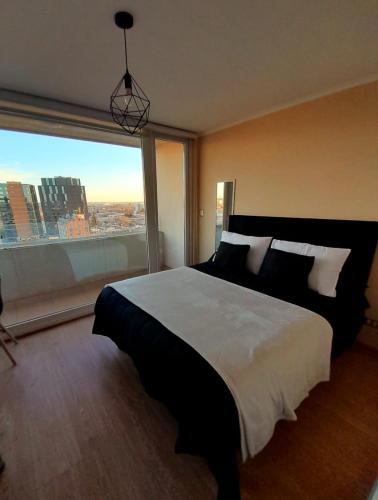 a bedroom with a large bed and a large window at Departamento en el centro de Chillán con estacionamiento, 709 in Chillán