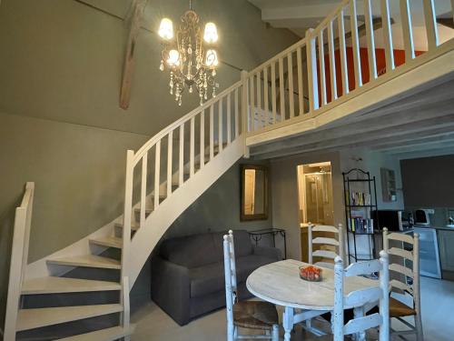 une salle à manger avec un escalier et une table dans l'établissement Le petit Pavillon, à Noyant-la-Plaine