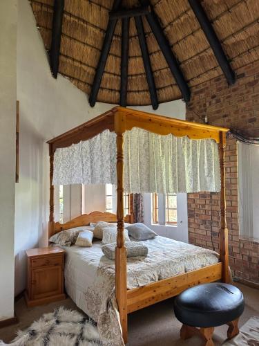 a bedroom with a wooden canopy bed with a ottoman at Okgethilwe Lodge in Sabie