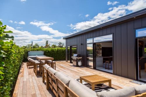 a deck with a couch and tables on a house at Sotally Tober Retreat in Martinborough 