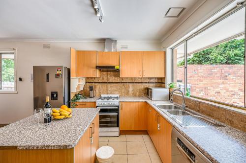 a kitchen with wooden cabinets and a large window at StayAU Family-Friendly 3BR Getaway in Malvern in Chadstone