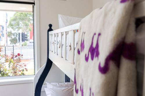 a white crib with purple paint on it next to a window at StayAU Family-Friendly 3BR Getaway in Malvern in Chadstone