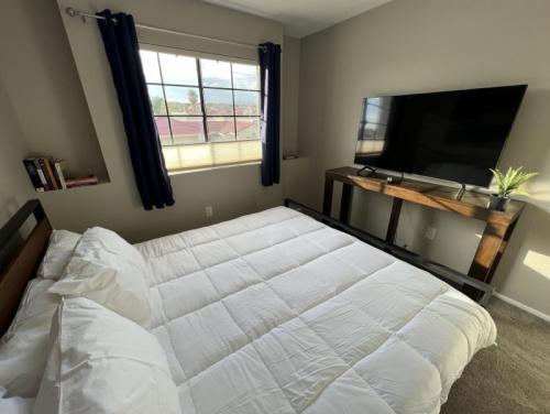 a bedroom with a white bed and a flat screen tv at Private Home - Billiards, Mountain Views, Private Desert Access, HOA Pool & Spa, BBQ, at Lambert Park - Bourbondale in Tucson